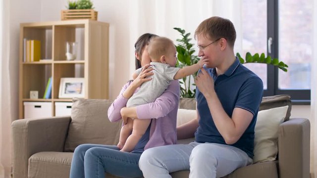 family, parenthood and people concept - happy mother and father with baby boy at home