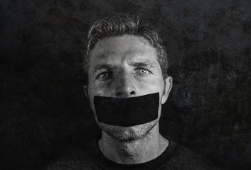 young man with mouth and lips sealed covered with adhesive tape in censorship coerced freedom of speech and forced silence and secrecy - obrazy, fototapety, plakaty
