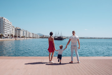 Fototapeta na wymiar Love and trust as family values. Mother and father with son look at bay with ship. Child with father and mother. Summer vacation of happy family. Family travel with kid on mothers or fathers day.