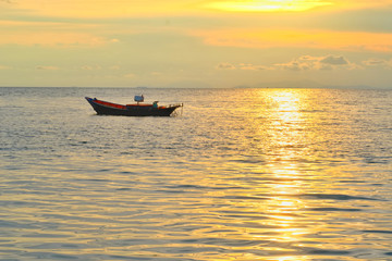Vacation time concept, A boat going and parking in the sea with sunset time or golden time and cloud in the background.