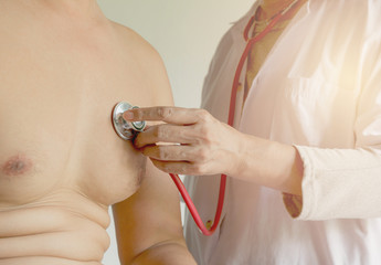 Fototapeta premium Female doctor using stethoscope for check and listen to heart and lungs of patient at a hospital.