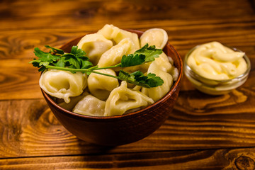 Fresh dumplings in ceramic bowl on wooden table