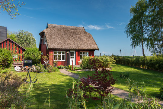 Sch&ouml;ner Garten eines typischen Dorfhaus mit Reetdach an der Ostsee