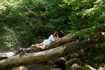 Pretty young woman in a white dress walking in the forest