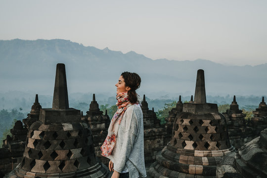 Beautiful young tourist feeling the peace of the great Borobudur temple, historical famous place in the java island Indonesia. Lifestyle and travel photography.