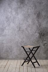 Bright vintage loft interior with wooden floor, textured aged grey plaster concrete on the wall and chair