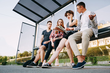 Traveling, sightseeing, group travel, city tour, togetherness. Lost in city tourists sit at bus stop searching the location on the map