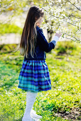 Adorable kid girl in blooming apple garden on beautiful spring day