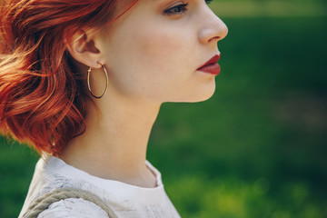 Close-up of a stylish woman wearing earrings on a summer day outside.