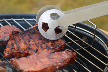 close up of tasty steaks on barbecue grill with Football World Cup tong