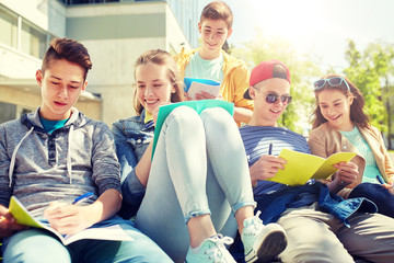 education, high school and people concept - group of happy teenage students with notebooks learning at campus yard