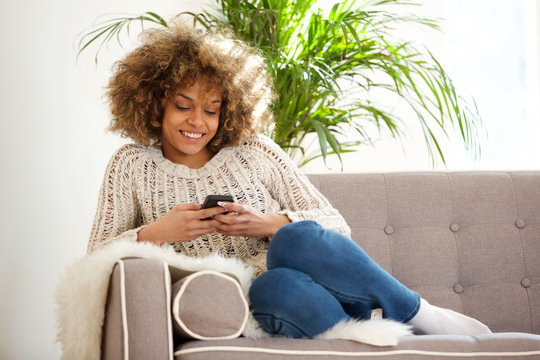 young african woman relaxing at home and using mobile phone