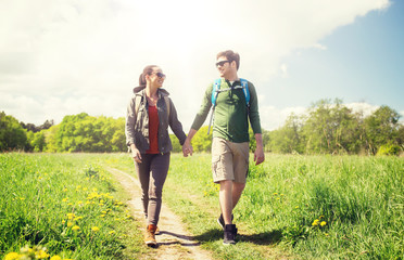 travel, hiking, backpacking, tourism and people concept - happy couple with backpacks holding hands...