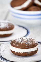Whoopie pies or moon pies, chocolate cake desserts filled with creamy frosting and decorated with powdered sugar