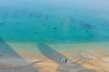 Several people on the beach of Kouki in Nago on Okinawa island in Japan. Beautiful turquoise water color of the South China sea.