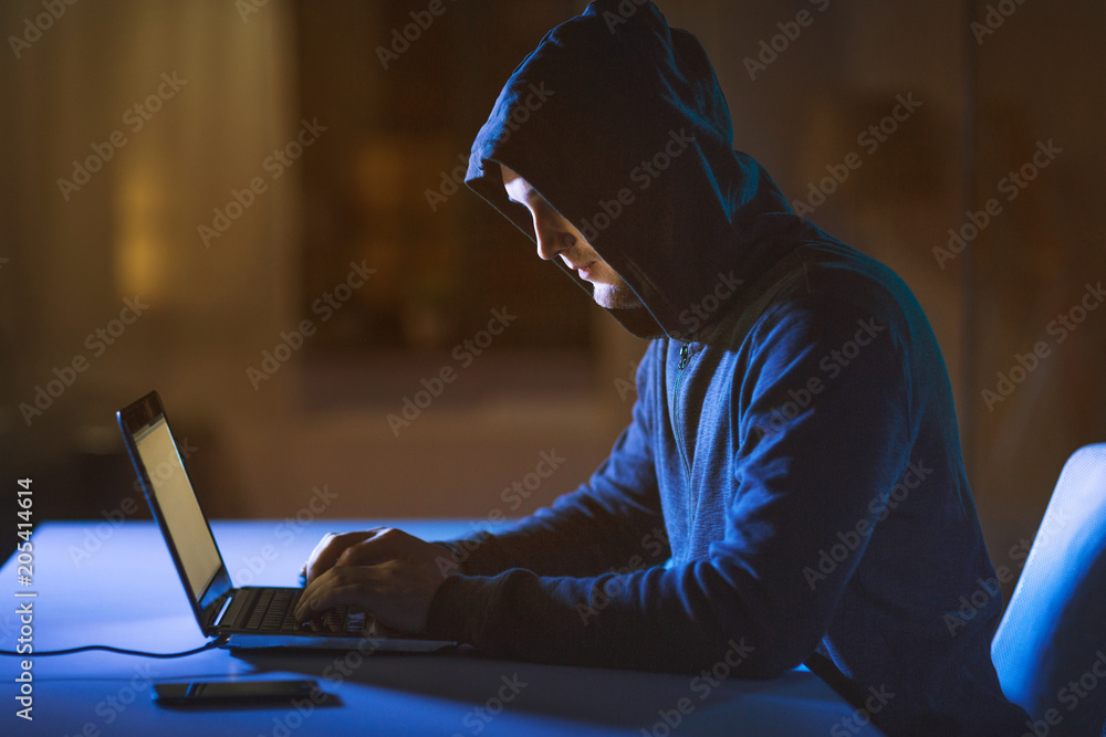 Poster cybercrime, hacking and technology crime - male hacker in dark room using laptop computer for cyber 