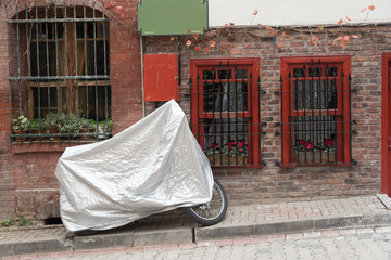 Motorcycle covered with a grey tarp about colorful houses in Istanbul