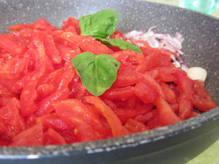 Cooking homemade tomato sauce using fresh summer tomatoes, onion, garlic and basil. Italian recipe
