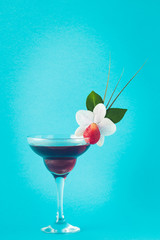 Mocktail decorated with strawberry, flower and tropical leaves.