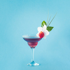 Mocktail decorated with strawberry, flower and tropical leaves.