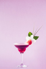 Mocktail decorated with strawberry, flower and tropical leaves.