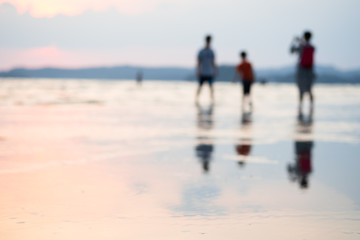 Fototapeta na wymiar Blurred background of people enjoying life on summer beach in sunset.