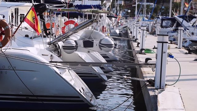 White boats and yakhts with Spanish flag waving in the wind. Sunny weather.