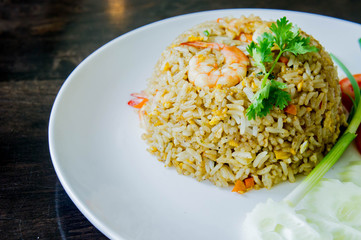 Fried rice with shrimp in a white dish on wood table in thai food style