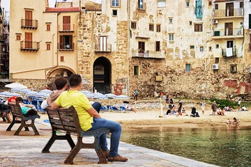 Fotobehang Seaside with people sitting on benches at Cefalu Sicily © Roman Babakin