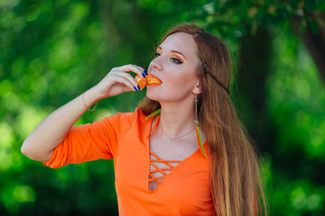 Fototapeta premium Portrait of pretty red hair woman with juicy delicious orange at summer green park.