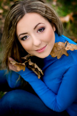 girl in blue sweater in autumn leaves