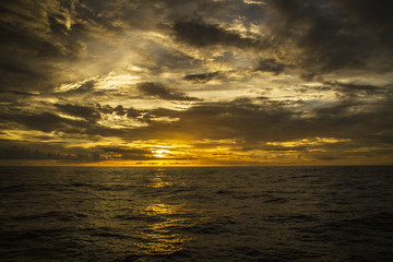 Naklejka premium Beautiful sunset on the ocean with a dramatic cloud and golden sunset sky 