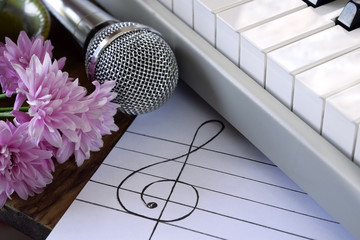 Treble clef and musical staff on white paper. Synthesizer, microphone and flowers around
