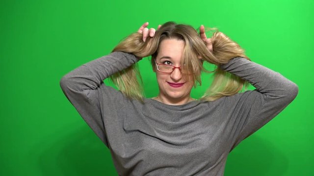 Young girl posing. Good mood. Performs arbitrary rhythmic movements. Plays with hair. Background green screen.