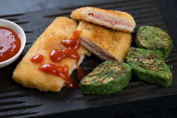 Close-up of sliced chicken cordon bleu with vegetable nuggets, selective focus