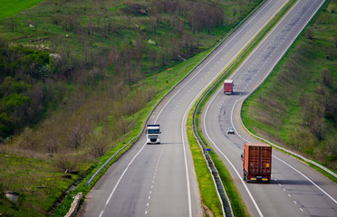 A hilly road with unseen horizon and driving lorries