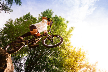 Young cyclist on the edge of a rock ready to jump