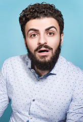 Portrait of a young man with a surprised face and open mouth. Stylish appearance, mustache and beard