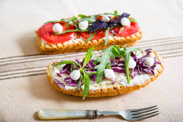 Toast with tomato, arugula, rucola, mozarella cheese, bread and greens