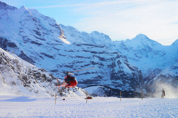 Naklejka na ściany i meble Helicopter flying near Swiss Alps mountains Maennlichen winter