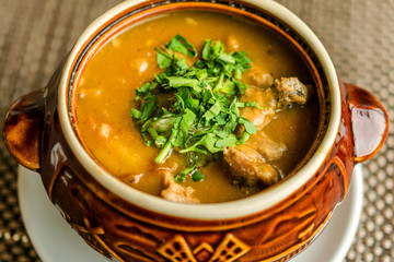 Delicious homemade goulash soup with meat and finely chopped parsley. In ceramic ware. Selective focus.