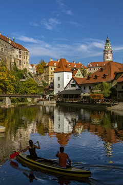 Cesky Krumlov, view on Vltava river and castle reflected in water . Boat with people rafting along the  river in the sunny day. Czech Republic.Historical city. European travel.