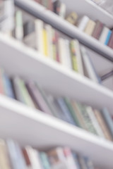 Abstract blurred bookshelves with books in public library, book store, at home, modern light...