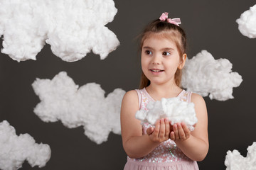 girl holding a cloud in her hands, shot in the studio on a gray background