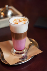 Trendy beetroot lattes with serving silver spoon. Hot coffee latte with cream. Pink latte coffee served for breakfast.