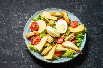 Fresh caesar salad in plate on black stone table