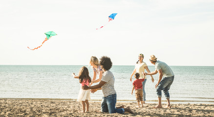 Group of happy families with parent and children playing with kite at beach vacation - Summer joy...