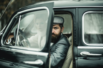 Escort of girl by security. Travel and business trip or hitch hiking. Retro collection car and auto repair by mechanic driver. Bearded man and sexy woman in car. Couple in love on romantic date.
