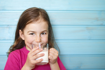 Cute little girl enjoys the taste of fresh milk