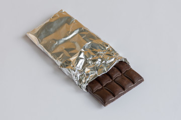  Dark chocolate bar in a foil on white background.